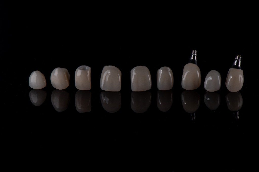 Range of dental crowns and implant restorations on a reflective surface